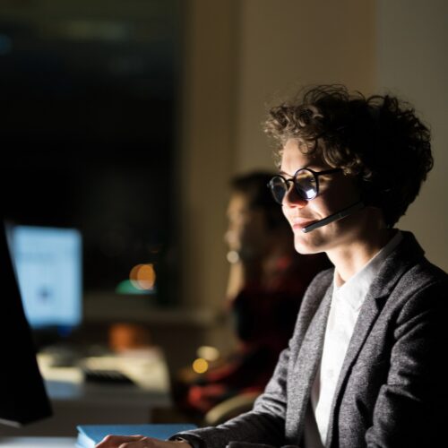 Customer service representative with headset smiling at laptop screen