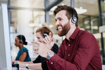 Customer service representative with headset smiling at his computer screen