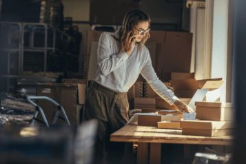Woman on the phone in a warehouse surrounded by boxes