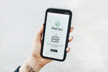 Woman holding mobile phone displaying an order confirmation